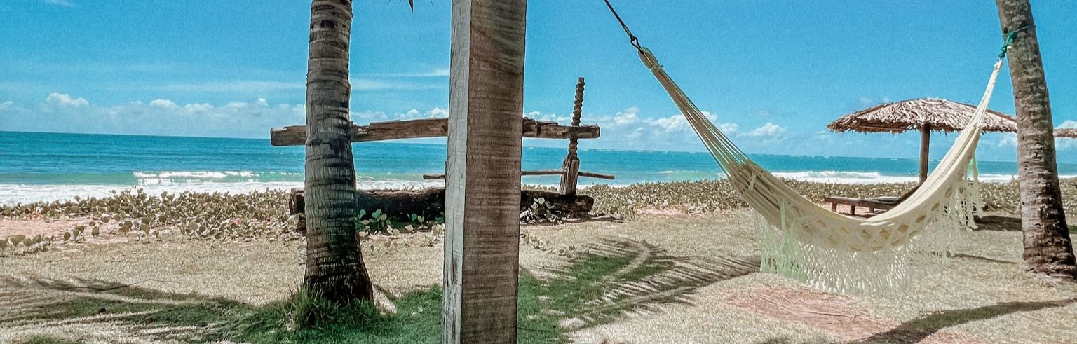 Banner: Rede na praia simbolizando a liberdade financeira de viver de renda