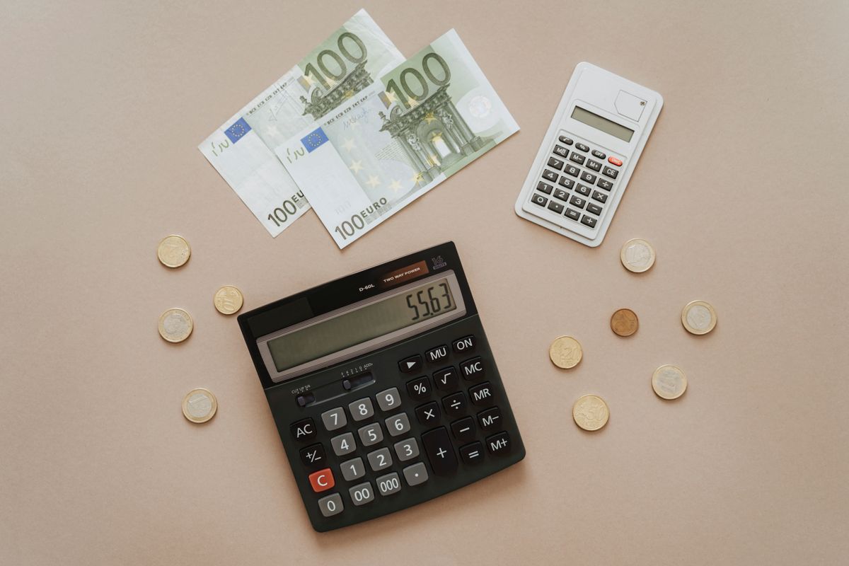 Calculadora, notas e moedas representando o lucro por acao