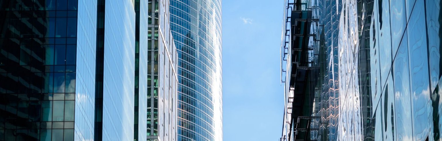 Prédios comerciais de vidro vistos de baixo, ilustrando os imóveis de um fundo imobiliário